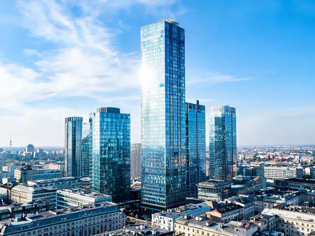 Panorama nowoczesnych polskich drapaczy chmur na tle jasnego nieba, z dominującą szklaną wieżą w centrum miasta.